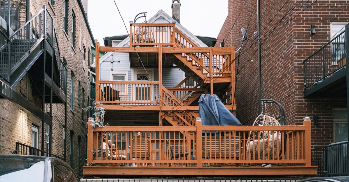 Multi-level wooden deck between urban buildings, showcasing unique architectural design.